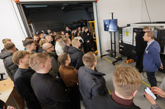 Grupa studentów obserwuje pokaz technologiczny przy stanowisku obróbkowym w hali produkcyjnej 