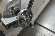 Zamocowany w uchwycie tokarskim element po obróbce, z widocznymi rowkami i precyzyjnie wykonanymi powierzchniami